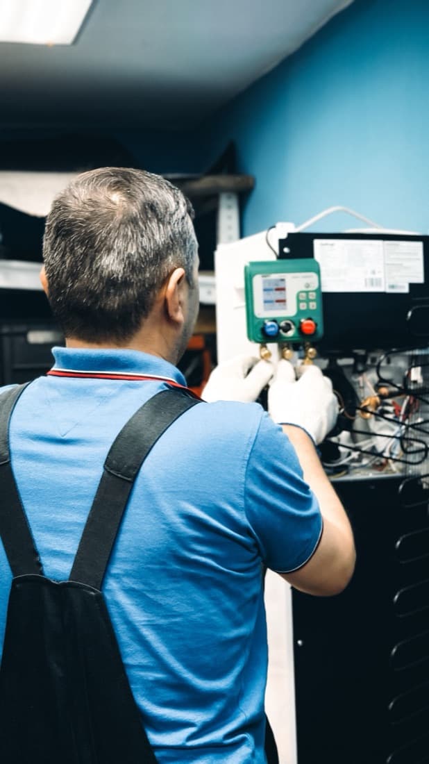 A technician holding a digital manifold gauge on a job