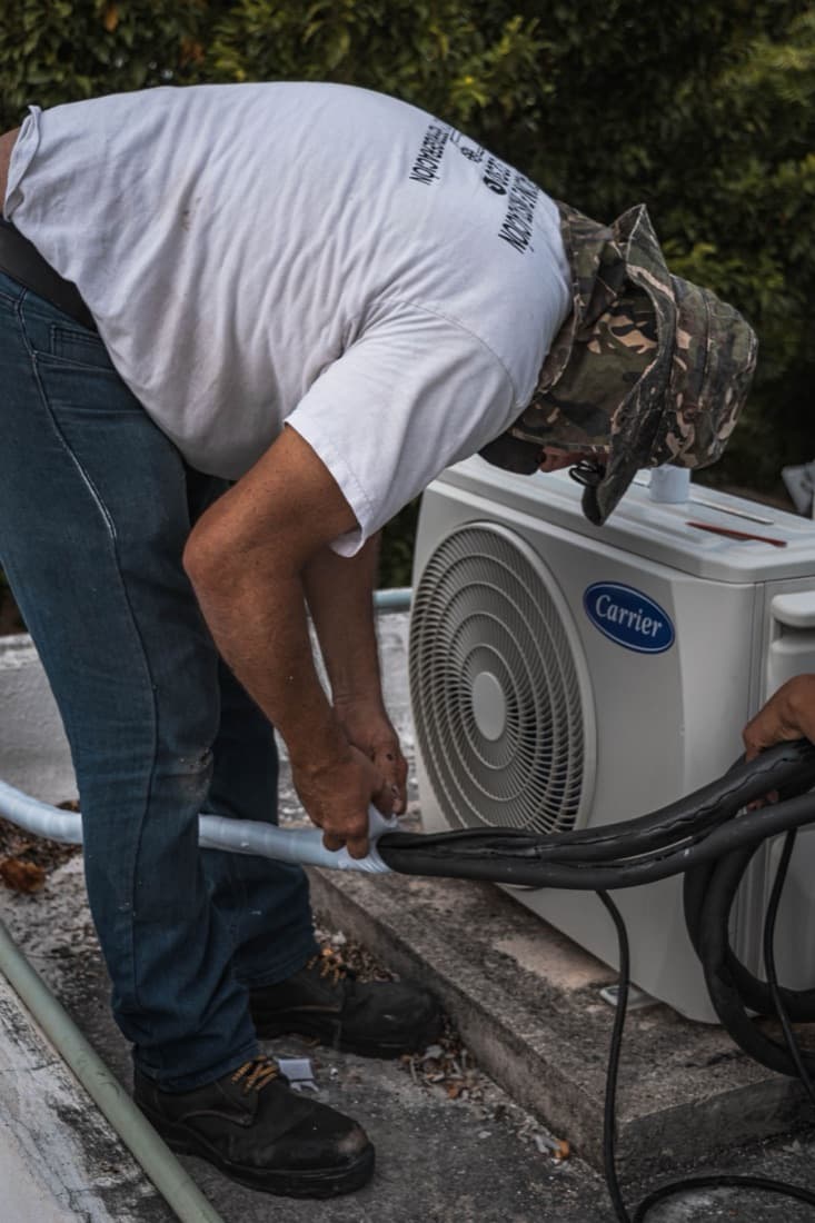 A technician connecting the lines on an air conditioning unit