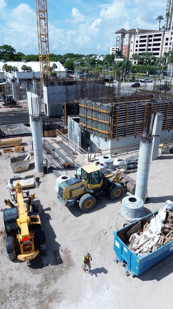 Aerial view of an active jobsite with a loader, a telehandler and a crew member