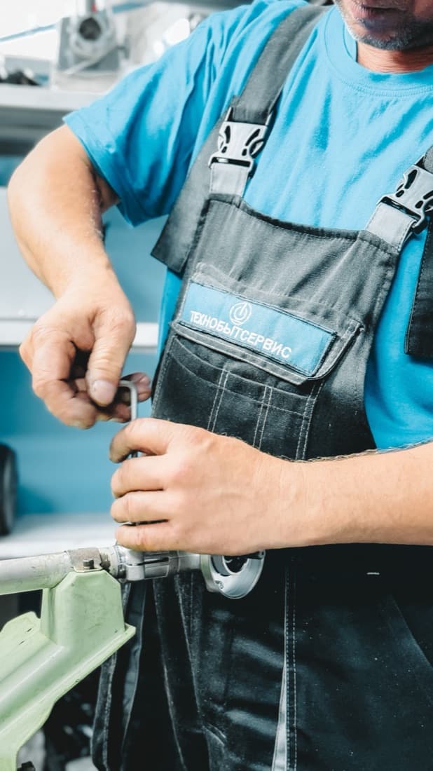 A plumber tightening a pipe fitting with a wrench