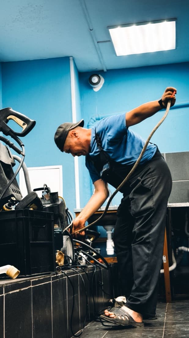 A plumbing technician at work in a utility room